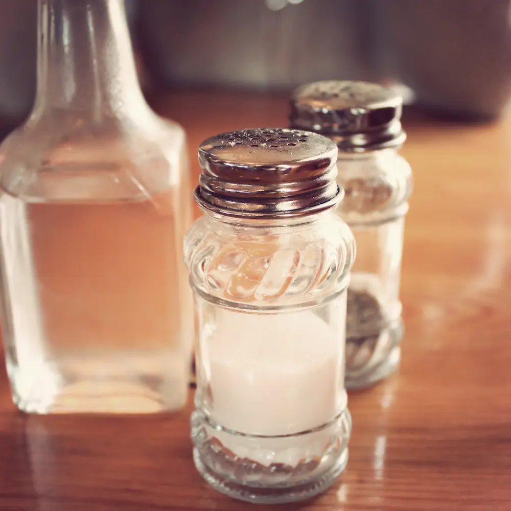 A set of condiments such as bottles of salt, pepper, and vinegar placed on top of a table.