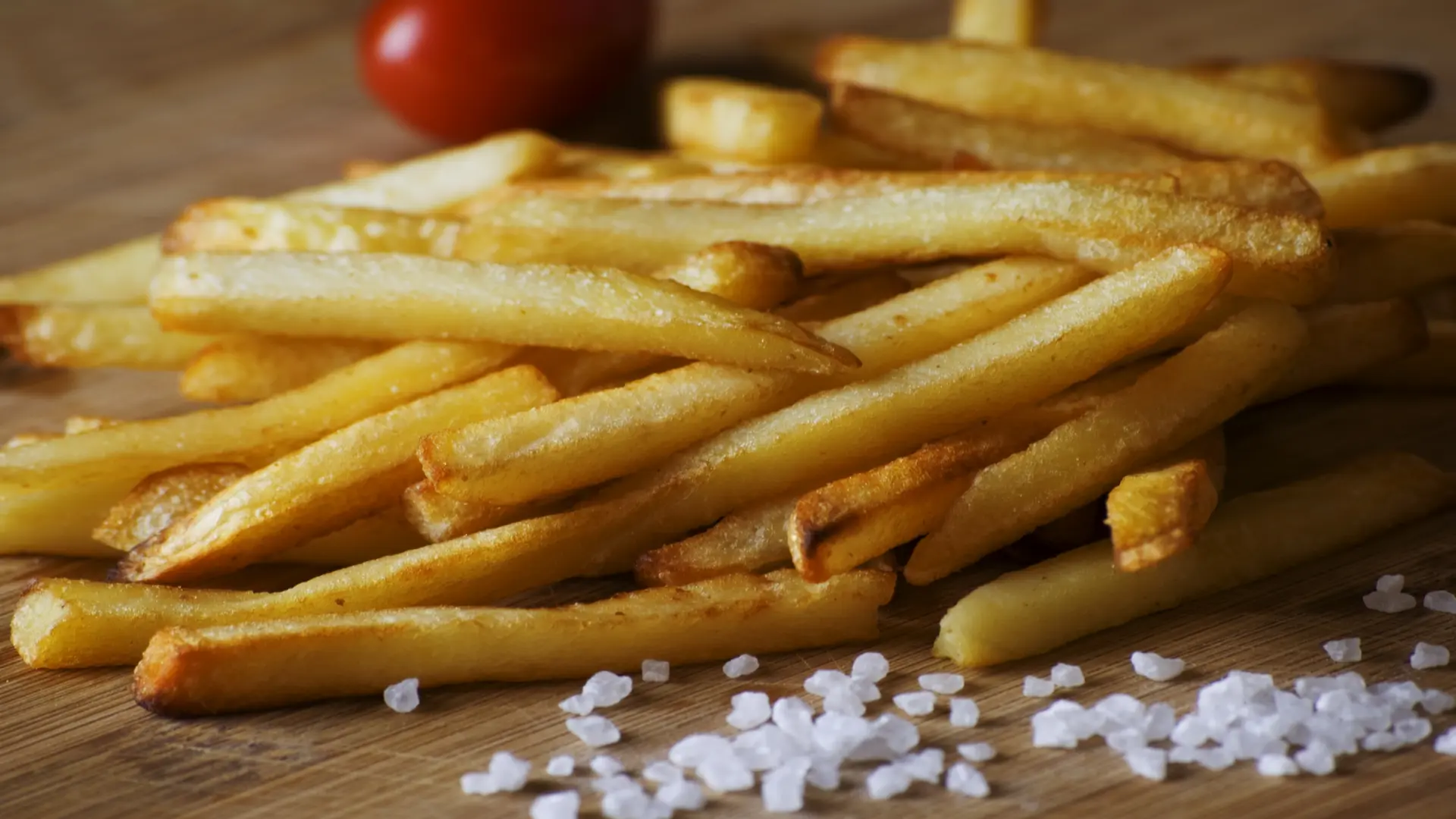 A photo of potato fries served on a dish with sea salt condiments.
